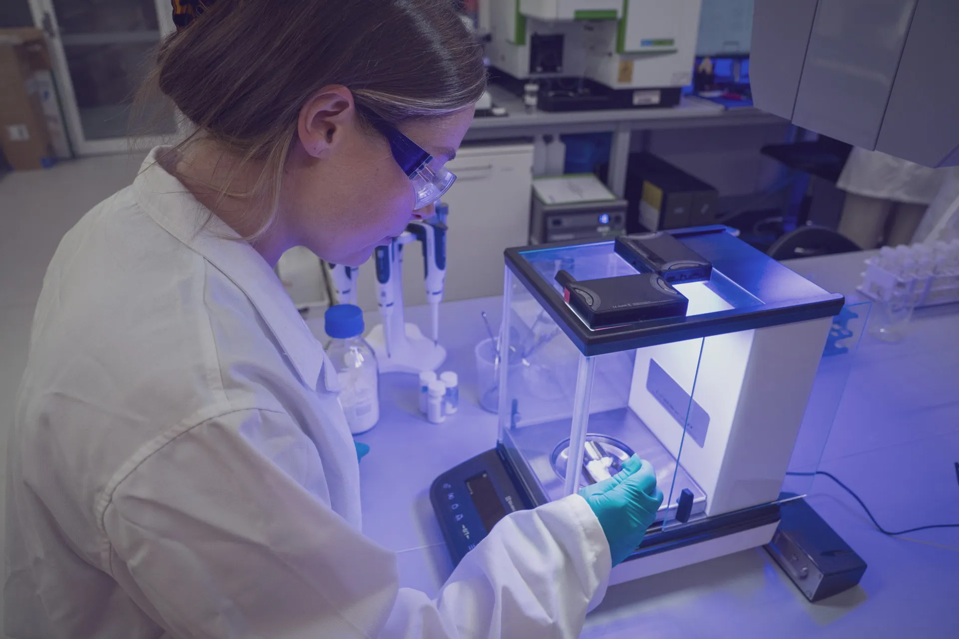 A Novalith scientist in a white coat, safety glasses and gloves weighs a sample of lithium carbonate on an analytical balance in the Sydney laboratory.